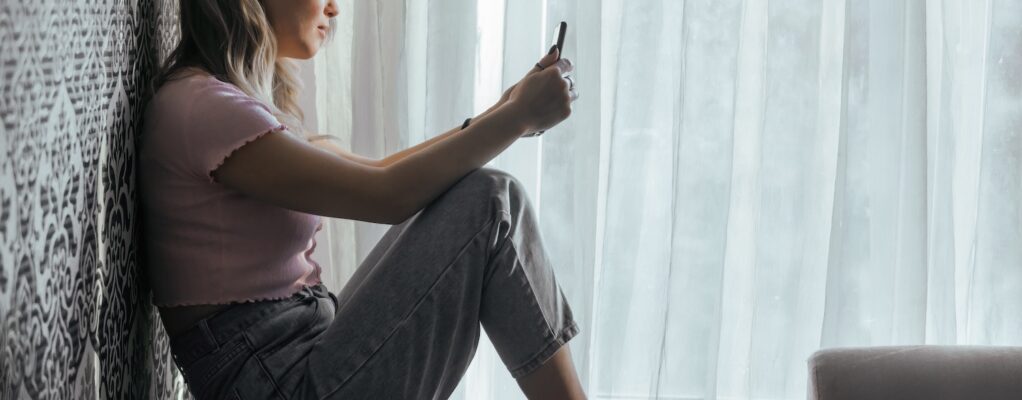 Sad teen girl looks at smartphone