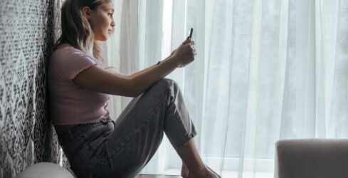 Sad teen girl looks at smartphone