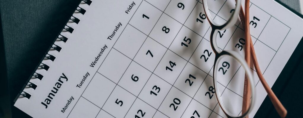 A close-up of a January calendar with eyeglasses on a table, emphasizing planning and organization.