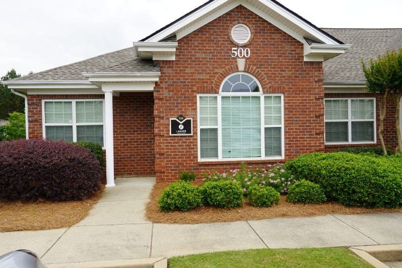 Brick house with white-trimmed windows, number 500, and a small sign reading 310 LAMIR in front of shrubs.